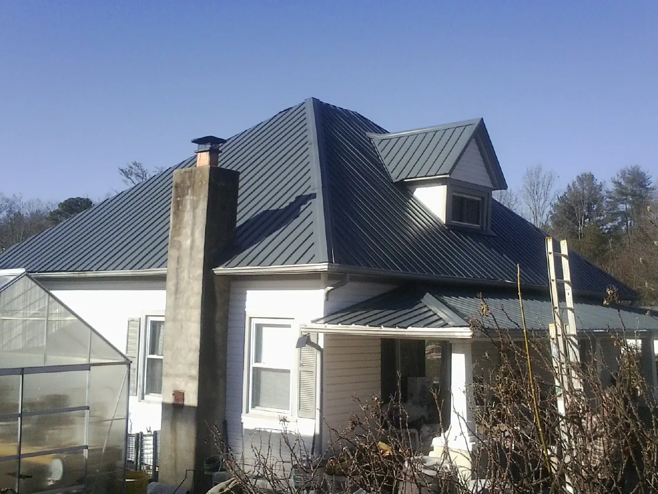 Dark blue standing seam metal roof on a white farmhouse with dormer — Slate & Tile Roof Repair by Roofing Brothers in Bryn Athyn