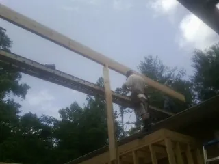 Carpenter setting a ridge beam over a new addition frame — Ice Dam Removal by Roofing Brothers in Bryn Athyn