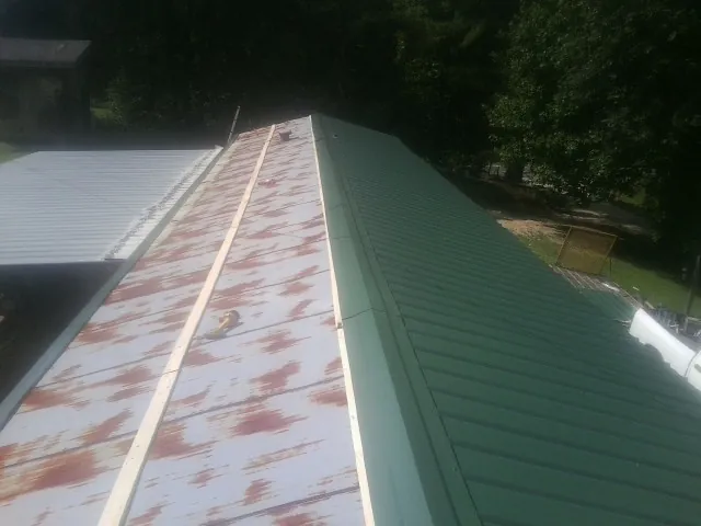 Old rusted panels beside newly installed green metal roofing — Wind Damage Roof Repair by Roofing Brothers in Bryn Athyn