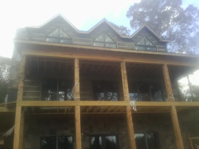 Dormers and porch framing on a large log home under construction — Roof Coating work by our crew in Bryn Athyn