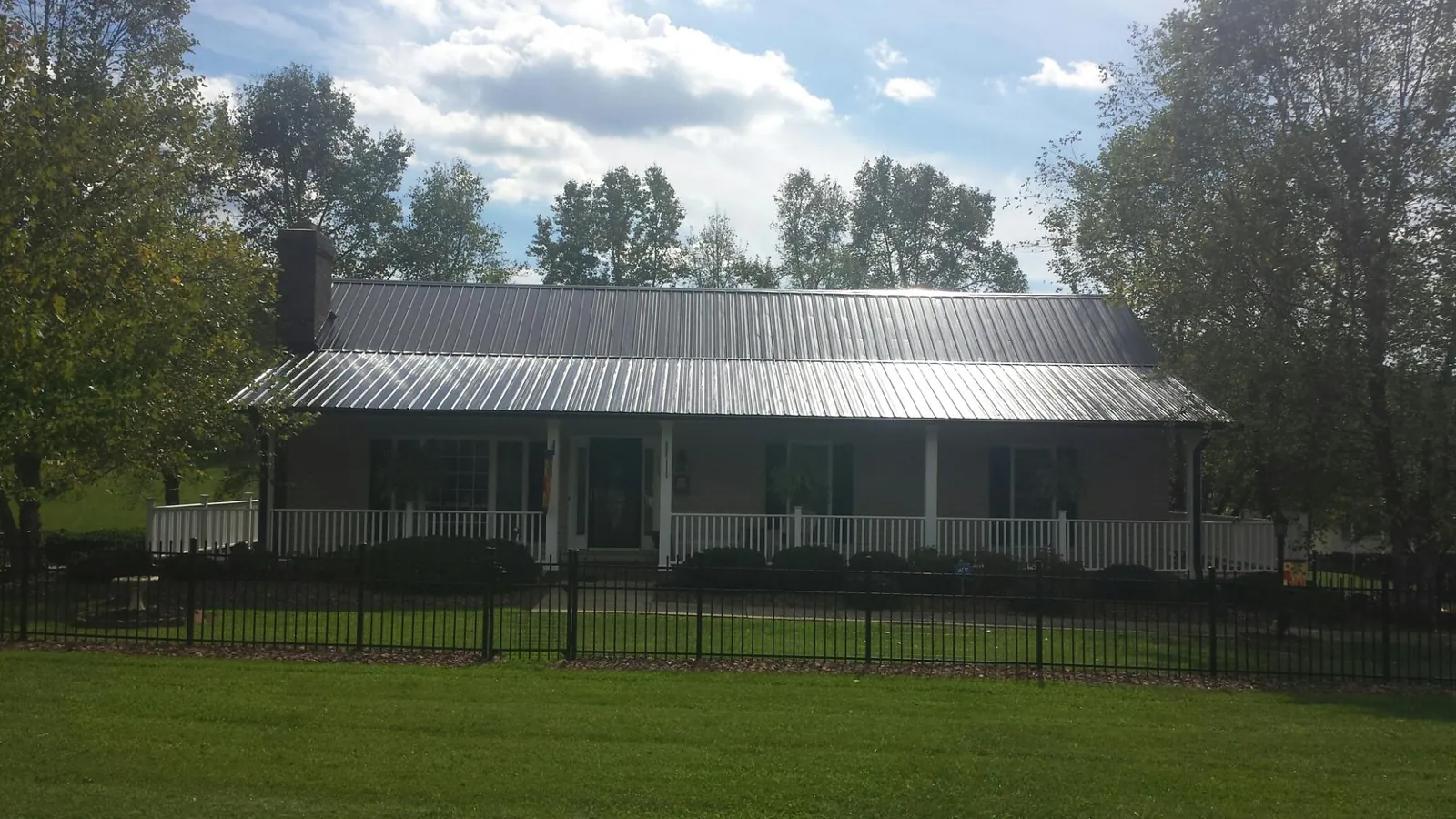 Gray metal roof on a brick ranch with a full width front porch — Gutter Guard Installation work by our crew in Bryn Athyn