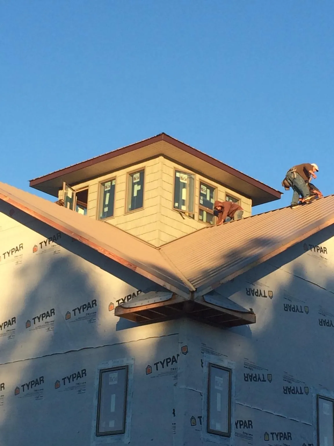 Roofers working around a rooftop cupola on a new metal roof at sunset — Roof Waterproofing in Bryn Athyn by Roofing Brothers